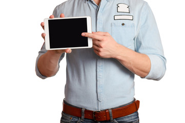 A man in a light blue shirt and jeans with a brown belt is holding tablet pc isolated on white background