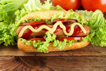 Hot dog with lettuce,tomatoes and salad on wooden board