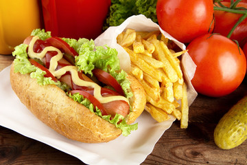 Hotdog with french fries on wooden plank