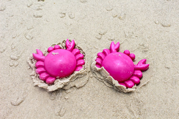 Fototapeta na wymiar A plastic pink crab sand toy on soft sand