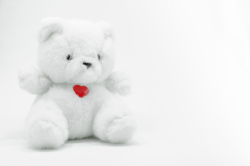 Lovely white teddy bear toy sitting with red heart on white background, fall in love teddy bear.