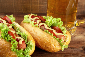 Hot dogs with glass of beer on wooden board