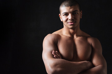 Fototapeta premium Cheerful young african sportsman standing with arms crossed