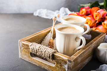 Two cups of coffee in vintage wooden tray with orange roses, copy space. Mother and Valentines day, wedding greeting card concept.