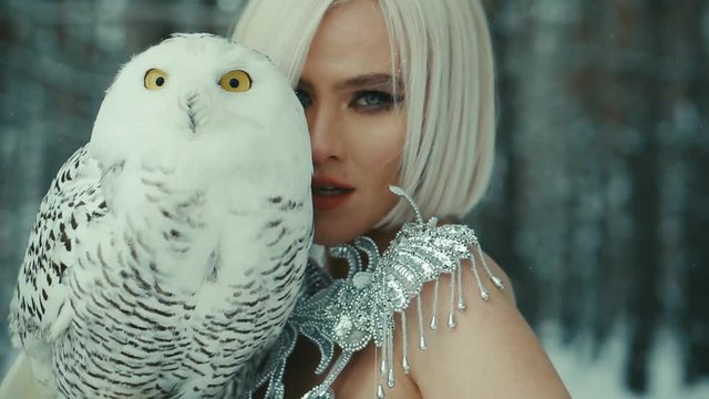 blonde with short hair posing with owl on background of a winter forest close-up