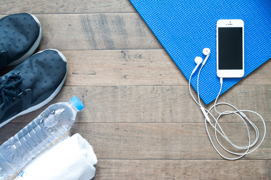 Overhead view of smartphone with earphone on blue yoga mat with