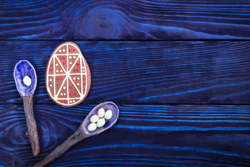 Happy holiday. Easter egg gingerbread and ceramic spoons on blue background