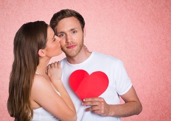 Fototapeta na wymiar Romantic woman kissing on the cheek of man holding a heart shape