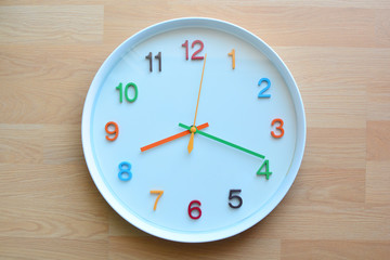 The colorful clock on the wooden floor background.