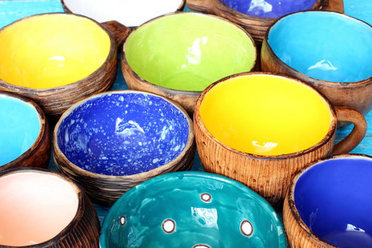 Many different bright multicolored ceramic bowls and cups handcrafted. Background texture