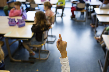 A child holds up het finger in order to ask a question in class.