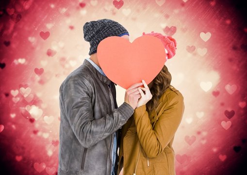 Romantic couple hiding their face behind heart