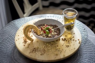Chocolatiers breakfast with oatmeal, puffed rice, cereals and dried strawberries and green tea prepared in a white bowl. Gold horseshoe for good luck.
