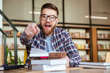 Smiling young student sitting at the desk in library