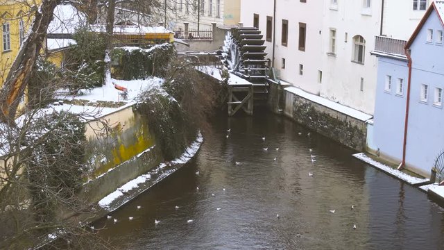 Canal and watermill near Charles Bridge in Prague under the snow in winter
