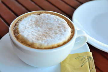 Coffee latte or cappuccino in a cup on wooden table