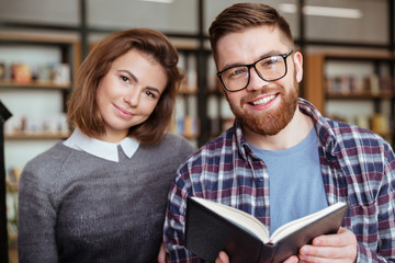 Happy man and woman preparing for exams in library