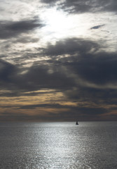 Dramatic evening seascape with sailing boat on dark sea