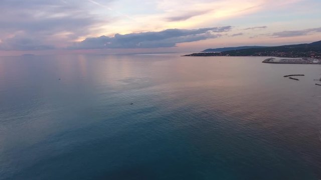 Aerial shot, incredibly beautiful calm sea in the sunset light with lots of clouds, filmed with drone