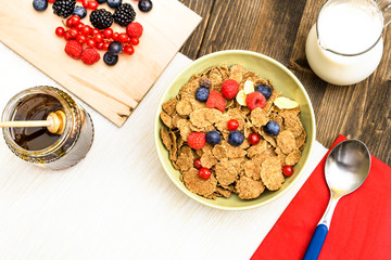    Breakfast bowl  with   wheat bran      cereal flakes and berries fruits top view on old wood table with milk and honey background 