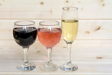 Glasses of red wine,rose and champagne isolated on a wooden  background