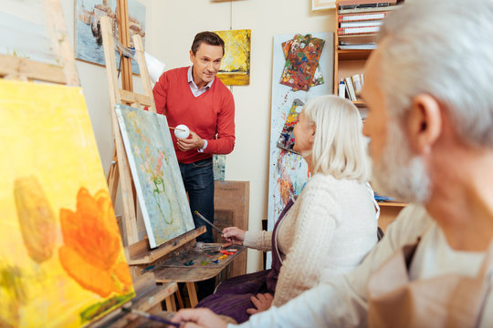 Delighted man teaching people in painting studio.