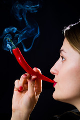 Woman hold smokineg red hot chili pepper like a cigarette - 135573400