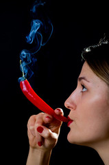 Woman hold smokineg red hot chili pepper like a cigarette - 135573409