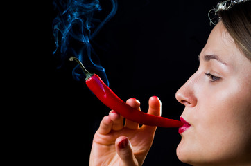 Woman hold smokineg red hot chili pepper like a cigarette - 135573432