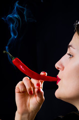 Woman hold smokineg red hot chili pepper like a cigarette - 135573445