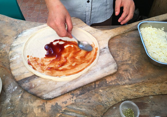 Man making a pizza on wooden desk closeup. 