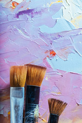 Fototapeta premium Close up of three brushes and colorful canvas