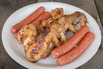 Grilled marinated chicken sausages and wings on white polystyren