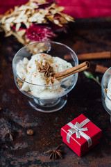 White ice cream with cinnamon and star anise on black rustic board.