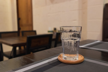 Glass of water with ice in restaurant dark room. selective focus