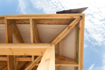 Corner of house with eaves, wooden beams and roof asphalt shingles