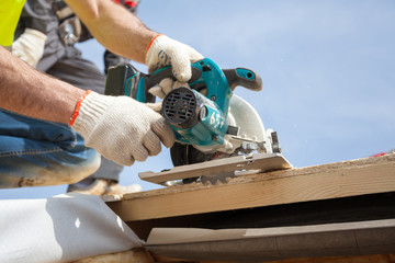 Installing a skylight. Construction Builder Worker use Circular Saw to Cut a Roof Opening for window