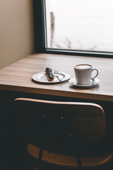 Cup of coffee on wooden table with eclair