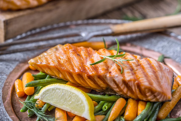 Salmon fillets. Grilled salmon, sesame seeds herb decoration on vintage pan or black slate board. fish roasted on an old wooden table.Studio shot.