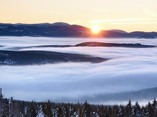 Pink orange sun rise above misty winter mountains