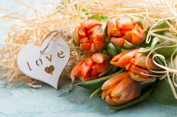 Orange tulips with wooden heart