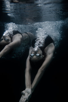 Two adult females swimming backstroke, underwater 