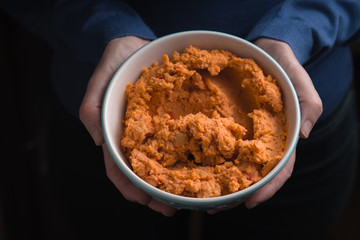 Bowl with hummus on the hands  top view