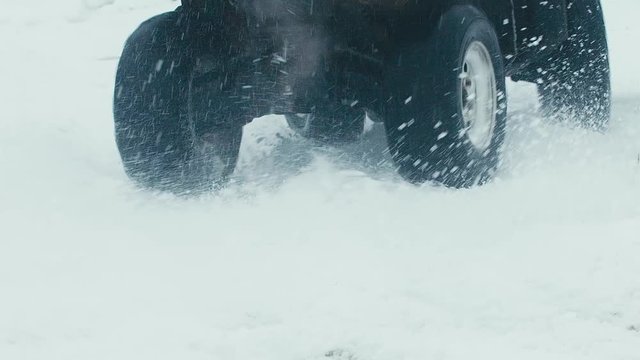 CU SLOW MOTION 120 FPS man driving an ATV quad bike in the winter field. 2K HD