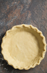 Raw homemade pie crust on a brown stone background. 