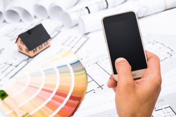 Male Hand holding a Smart Phone over Construction plans