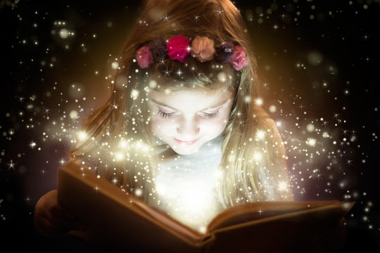 Beautiful little girl reading magic book