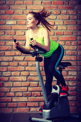 Active woman using exercise bike at the gym.