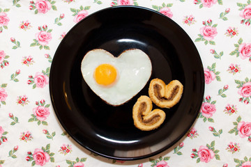Composition of biscuits and egg in a heart shape on black plate. Valentine's Day