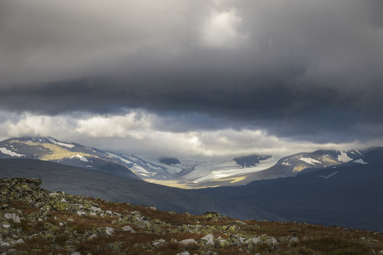 Ancient glaciers landscape in sunlight under stormy and dramatic sky © Wouter